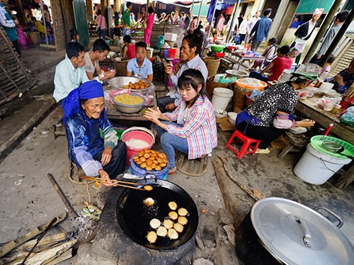 Người dân thưởng thức đặc sản bánh rán tại chợ.