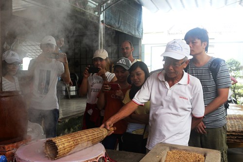  Chú Năm Nghiêm (ảnh, phải, hàng đầu) hướng dẫn du khách tráng bánh làm hủ tiếu tại Lò hủ tiếu Quê Tôi.