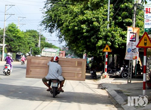 Xe máy chở cửa quá dài gây cản trở giao thông.