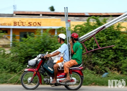 Xe máy chở vật dụng quá khổ gây trở ngại cho người đi đường. (Ảnh chụp lúc 13 giờ 50 phút ngày 2-10- 2014)