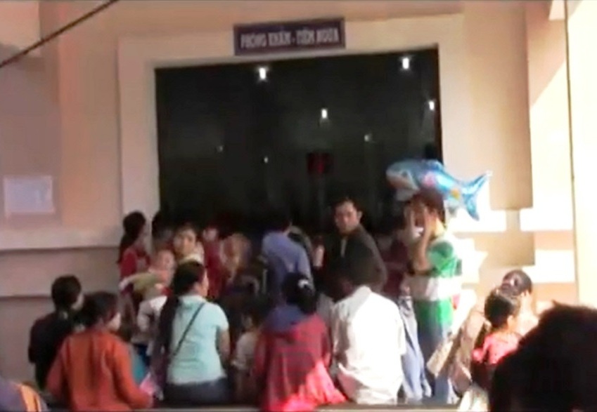 Phụ huynh ẵm con, mỏi mòn chờ tiêm phòng sởi