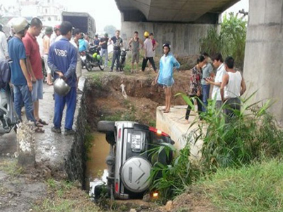 Ôtô 7 chỗ nằm lọt trong mương thoát nước cầu vượt