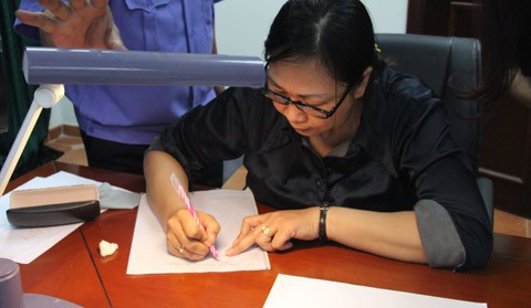 Bà Nguyễn Thị Thanh Vân đang thực nghiệm lại hành vi làm giả giấy tờ trước cơ quan điều tra.