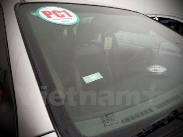  Thẻ E-tag (hình chữ nhật) được dán trên kính xe phía bên trái của tài xế điều khiển, tính phí tự động với trạm thu phí theo công nghệ không dừng. (Ảnh: Việt Hùng/Vietnam+).
