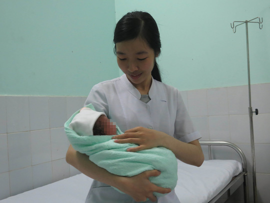  Bé trai mới sinh trong vòng tay một nữ hộ sinh của Bệnh viện Quận Gò Vấp