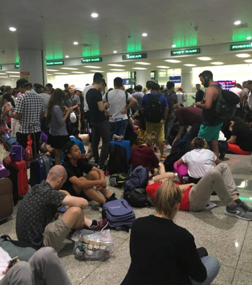 Nhiều hành khách mệt mỏi nằm vạ vật chờ ngay khu vực làm thủ tục nhập cảnh ở sân bay Nội Bài - Ảnh: B.Đ